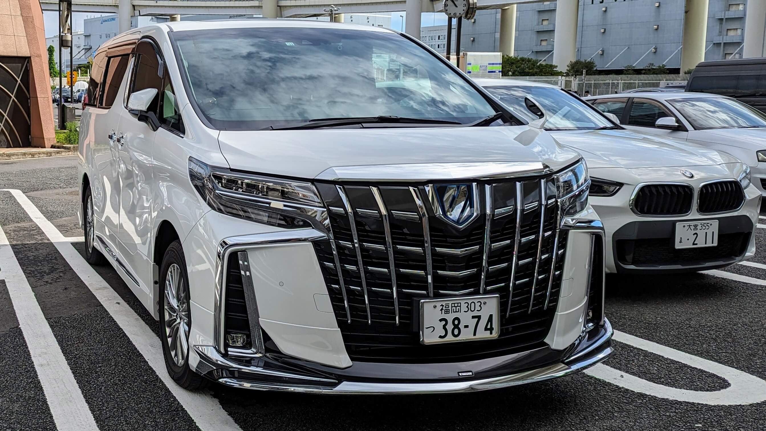 A white Toyota Alphard family van at Daikoku Parking Area in Yokohama, Japan